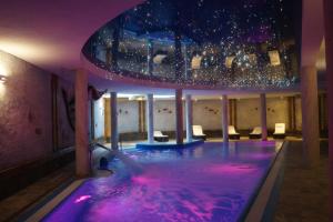 una piscina en una habitación con iluminación púrpura en Hotel Kryształ Conference & Spa, en Szklarska Poręba