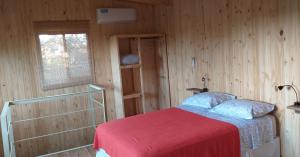 a bedroom with a bed with a red blanket and a window at Cabaña Oma in Puerto Iguazú