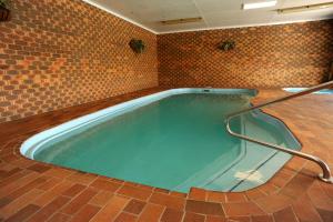 einen großen Pool in einem Zimmer mit Ziegelwand in der Unterkunft Horsham Mid City Court Motel in Horsham