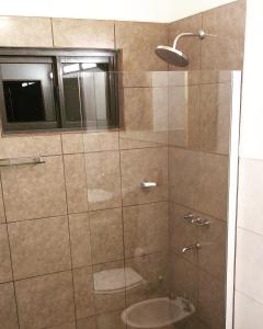 a bathroom with a shower with a toilet and a window at Cabaña Oma in Puerto Iguazú