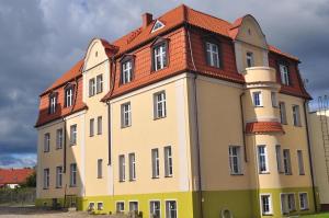 een groot gebouw met een rood dak bij Hotelik Hermes in Pieniężno