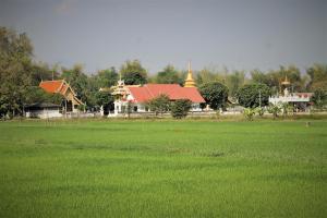 um grande campo de relva verde com uma igreja ao fundo em Country Retreat em Mae Rim
