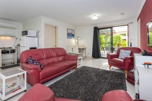 un soggiorno con un divano rosso e 2 sedie di Altona Garden Retreat a Spreyton