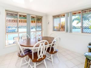 a dining room with a table and chairs and windows at Seachange in Yamba