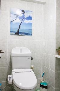 y baño con aseo y una pared con una pintura de palmera. en イオンモール沖縄ライカムまで車で10分のスカイテラス8階, en Okinawa City 6 fotos más
