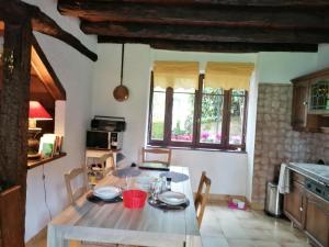 a kitchen with a wooden table and a table and chairs at Au pays des abbayes in Dourgne