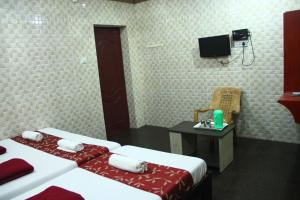 a hotel room with two beds and a tv at Hotel Temple Tower Rameswaram in Rāmeswaram