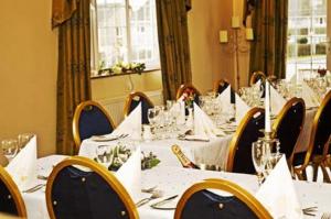 uma sala de jantar com mesas e cadeiras brancas em Solway Lodge Hotel em Gretna Green