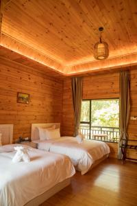 Dos camas en una habitación con paredes de madera. en Dansavanh Namngum Resort, en Ban Keun