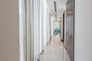 a corridor with white curtains and a long hallway at Paradise Nurai Villa - 6 Bedrooms in Abu Dhabi