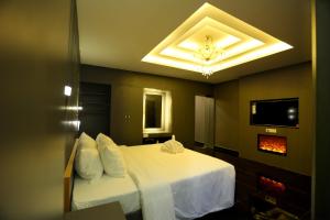 a bedroom with a white bed and a tv at Mehar Inn Hotel in Kāraikkudi