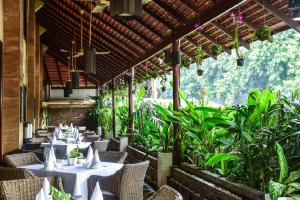 a restaurant with tables and chairs and plants at Almond Hotel Sothearos in Phnom Penh