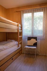 a bedroom with two bunk beds and a chair and a window at Ferienwohnung Helios in Adelboden