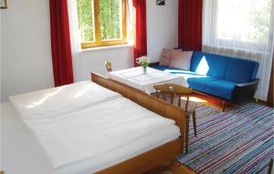 a bedroom with two beds and a blue couch at 3 Bedroom Gorgeous Apartment In Stumm in Stumm