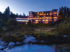 厄茂Schloss Elmau Luxury Spa Retreat & Cultural Hideaway的河前灯火的大建筑