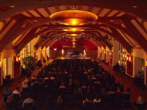 a group of people sitting in a hall with a piano at Schloss Elmau Luxury Spa Retreat & Cultural Hideaway in Elmau