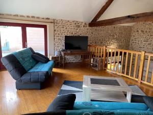 a living room with a couch and a tv at Du côté de chez Sam in Andelaroche