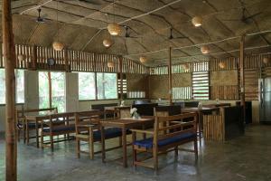 a restaurant with wooden tables and chairs and windows at Havelock Farms Resort in Havelock Island