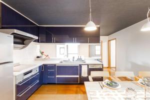 札幌市にあるTHE WORLDWIDE HOUSE の青いキャビネットとテーブル付きのキッチンが備わります。