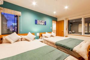 - 2 lits dans une chambre avec un mur vert dans l'établissement THE WORLDWIDE HOUSE, à Sapporo