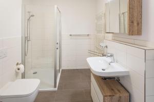 een witte badkamer met een wastafel en een douche bij Ferienwohnung Meeresrauschen in Ostseebad Sellin