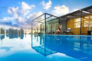 a woman sitting on a chair next to a swimming pool at Bay Hotel Ho Chi Minh in Ho Chi Minh City