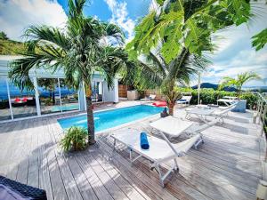 a swimming pool with two lounge chairs and palm trees at Villa SEA VIEW, 5 min from the beach, overlooking the caribbean sea, private pool in Friar's Bay