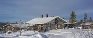 ein Blockhaus mit Schnee darüber in der Unterkunft Sielikkö Aurora Log Apartments in Saariselkä