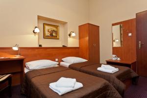 a hotel room with two beds with towels on them at Hotel Maksymilian in Krakow
