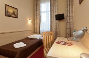 a hotel room with a bed and a desk with a table at Hotel Maksymilian in Krakow