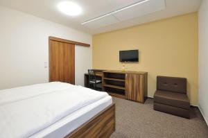 1 dormitorio con 1 cama, 1 silla y TV en Penzion Kuželna, en Trutnov