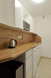 una cocina con armarios blancos y tetera en una encimera. en Penzion Kuželna, en Trutnov