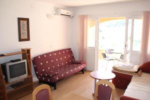 ein Wohnzimmer mit einem Sofa und einem TV in der Unterkunft Guest House Katić in Trpanj