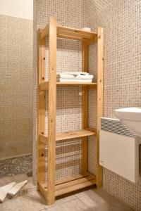 y baño con ducha, estantes de madera y lavamanos. en Flórián Vendégház, en Villánykövesd