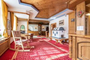 a living room with a table and chairs and a wooden ceiling at MyTime Hotels Savoy in Vigo di Fassa