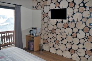 a bedroom with a wall covered in logs at Locanda La Baita in Santo Stefano di Cadore