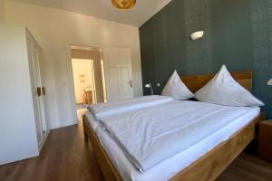 um quarto com uma cama grande com lençóis brancos e almofadas em FeWoEcK Optimist em Eckernförde
