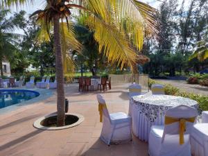 a table and chairs and a palm tree next to a pool at coral beach resort in Mahabalipuram