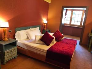 Un dormitorio con una cama con almohadas rojas y una ventana en Hotel Punta Maquignaz, en Breuil-Cervinia