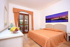 a bedroom with a bed and a bowl of fruit on a table at Hotel Punta Negra in Alghero