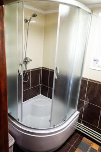 La salle de bains est pourvue d'une douche avec une porte en verre. dans l'établissement Домашня Оселя, à Yaremtche