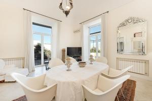 ein weißes Esszimmer mit einem Tisch und Stühlen in der Unterkunft Casa Bormioli - Maison de Charme in Procida