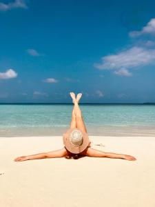 uma mulher de chapéu deitada numa praia em Island Break em Fulidhoo