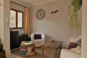 a living room with a chair and a table and a clock at Gites de la Lurette - agréable T2 indépendant dans cadre calme et verdoyant in Cazilhac