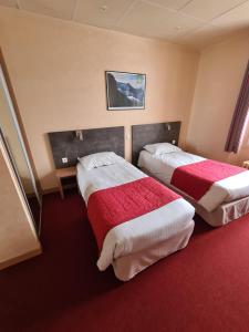 ミュラにあるHOSTELLERIE du CANTALのベッド2台 ホテルルーム レッドカーペット付