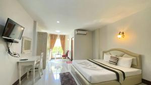 Dormitorio con cama, escritorio y TV en The Target Residence, en Chiang Rai