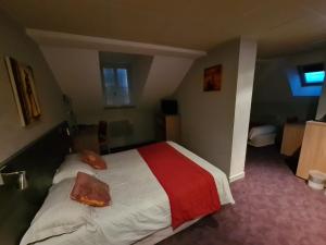 Cette chambre d'hôtel comprend un lit avec des draps rouges et blancs. dans l'établissement HOSTELLERIE du CANTAL, à Murat