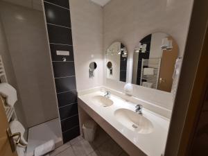 a bathroom with two sinks and a mirror at HOSTELLERIE du CANTAL in Murat