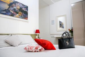 Bolso negro sobre una cama con almohadas rojas en Al Parco II Rota B&B, en Sorrento