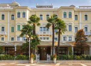 a large yellow building with palm trees in front of it at Grand Hotel Trieste & Victoria in Abano Terme